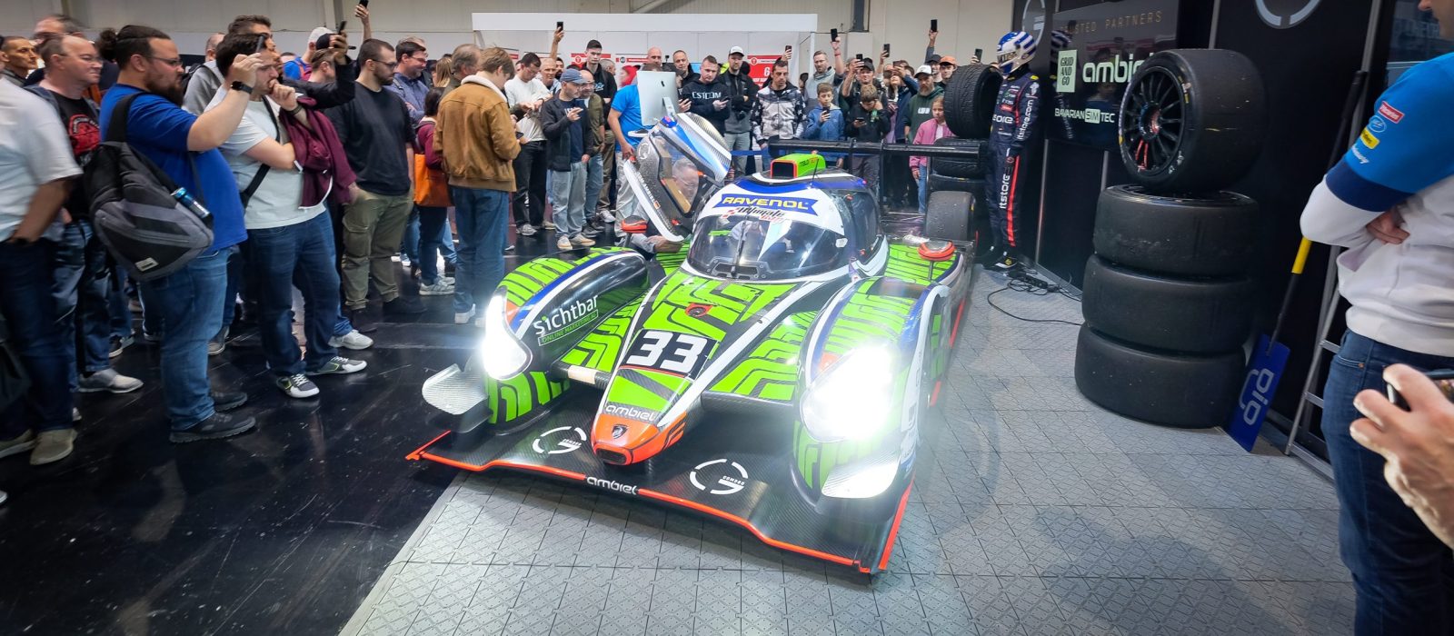 GCOM360 booth at SimRacing Expo 2025 featuring an LMP3 race car
